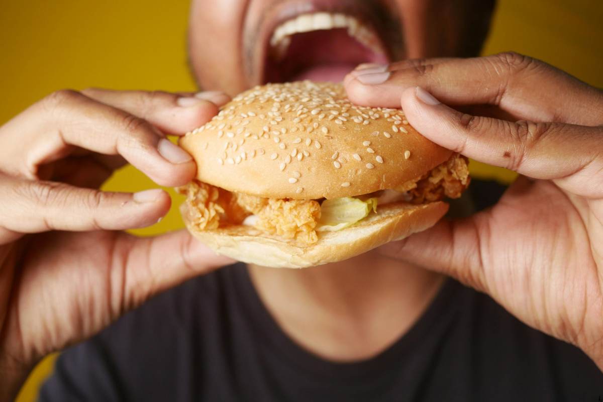 Persona mangia con foga un hamburger