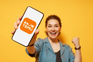 Ragazza felice che mostra uno smartphone con il logo di Temu sullo sfondo