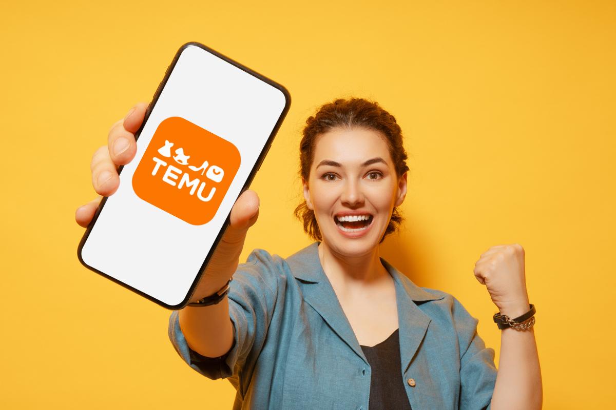 Ragazza felice che mostra uno smartphone con il logo di Temu sullo sfondo