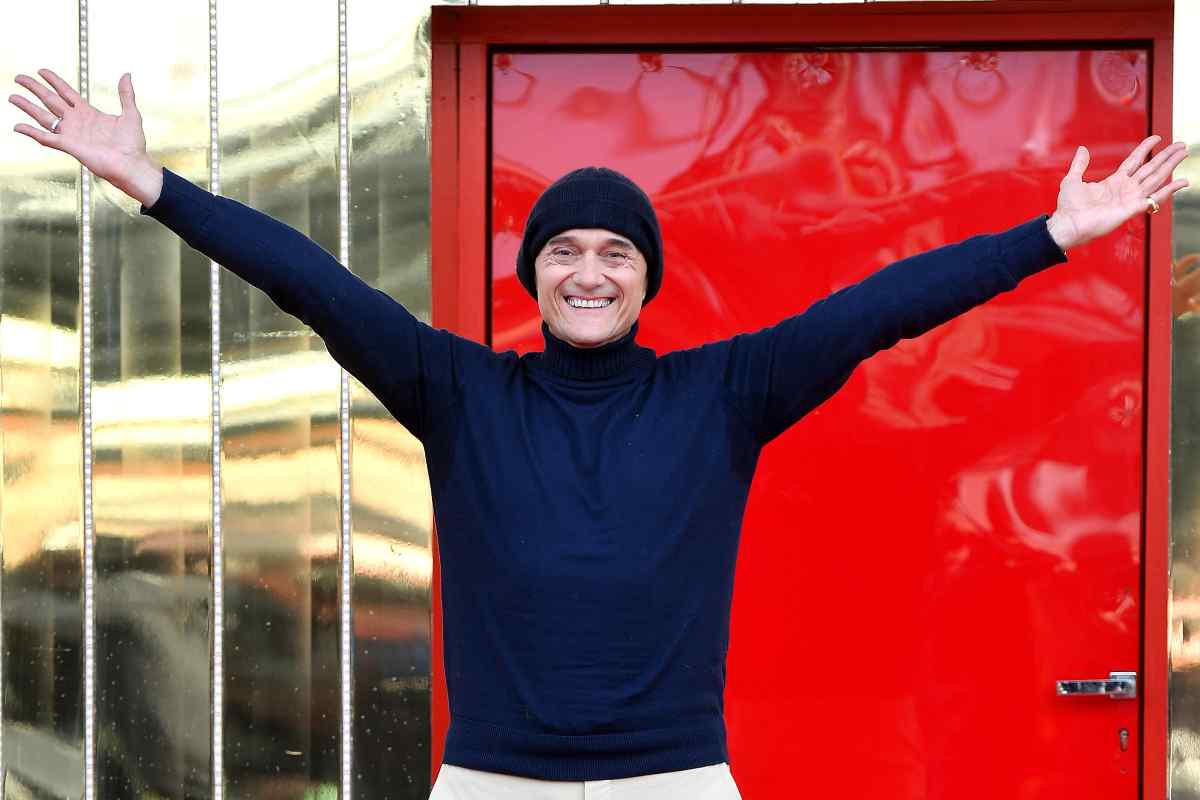Alfonso Signorini a braccia aperte davanti alla Porta Rossa