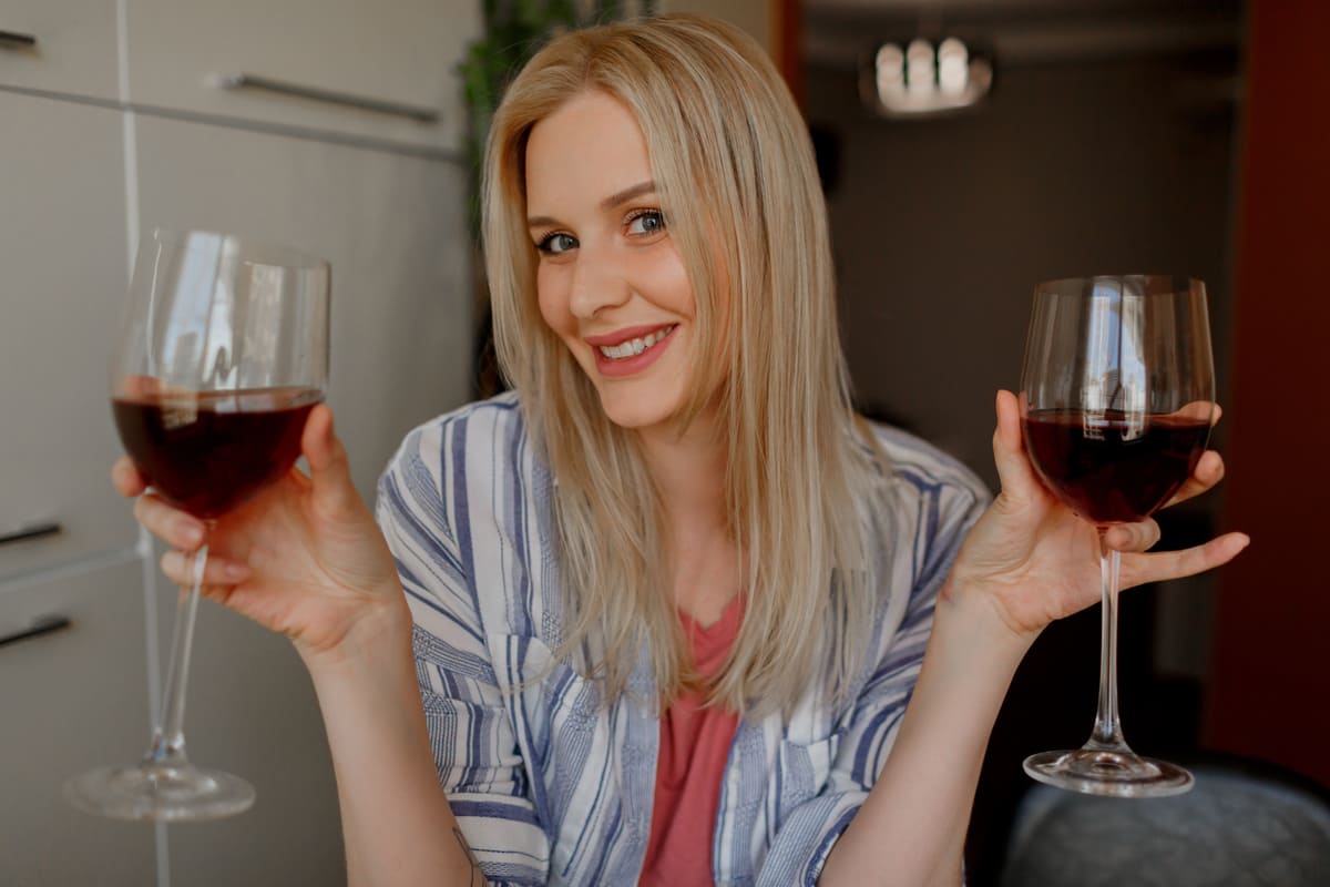 Donna che tiene in mano due bicchieri di vino rosso