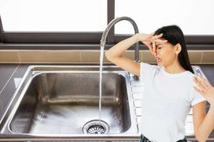 Donna si tappa il naso, lavandino con acqua che scorre