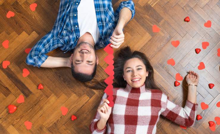 Un uomo e una donna sdraiati sul pavimento con cuoricini rossi di carta