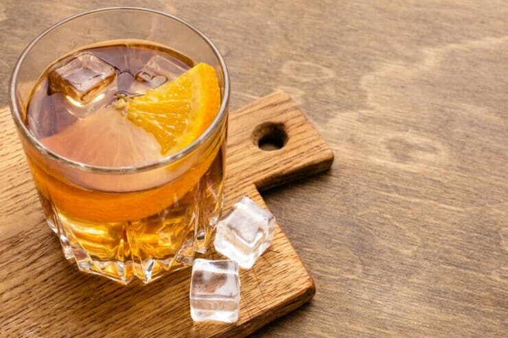 Bicchiere di whiskey e ghiaccio guarnito con arancia