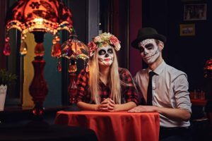Coppia con trucco da Halloween seduta a un tavolo