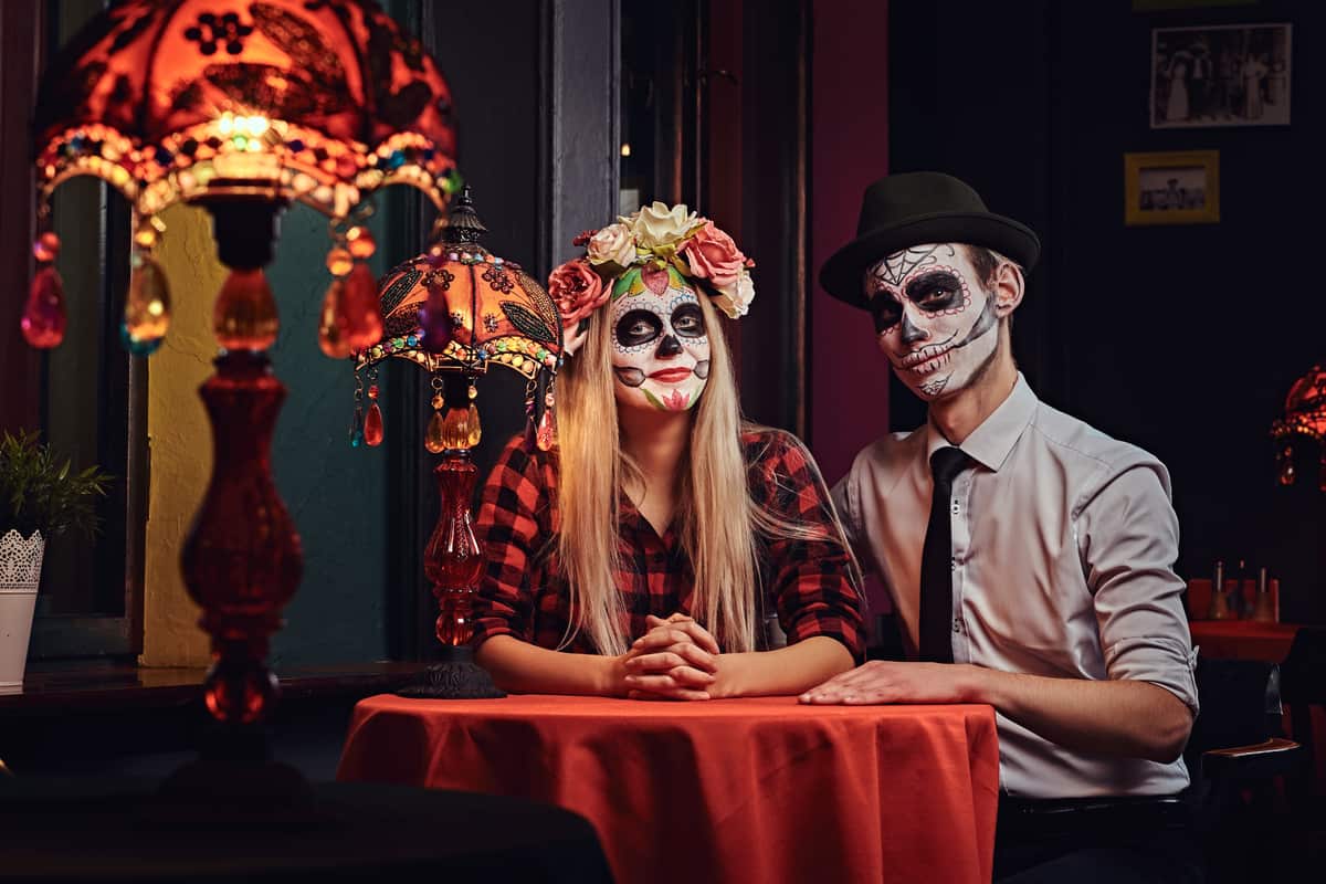 Coppia con trucco da Halloween seduta a un tavolo