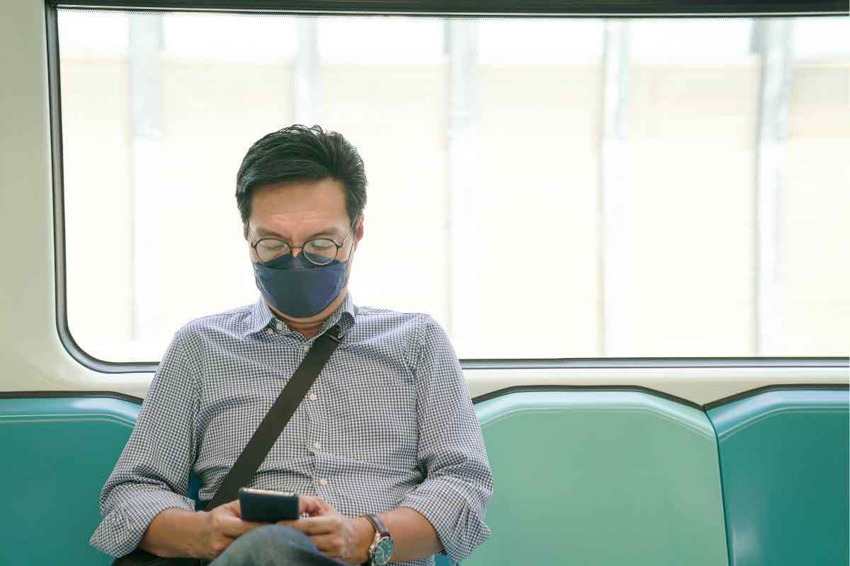 uomo in treno con mascherina sul viso