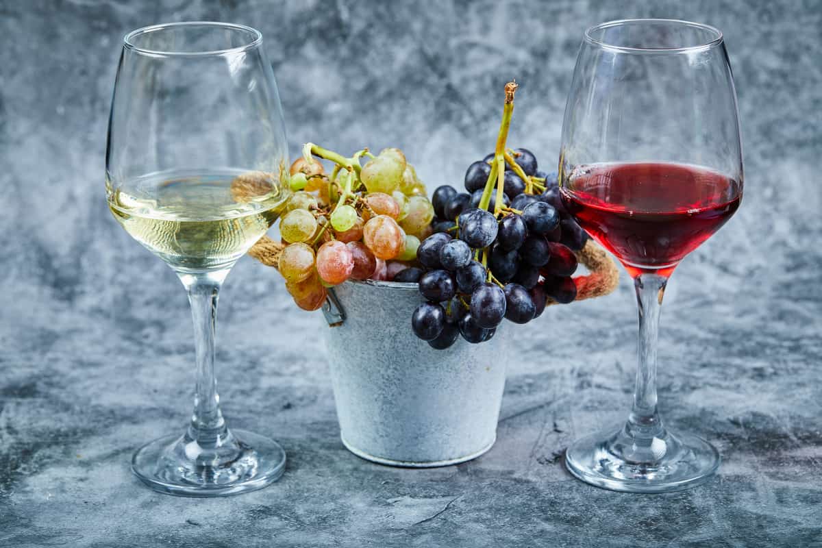 Bicchiere di vino bianco e rosso con uva al centro