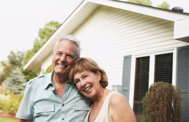 uomo e donna che sorridono davanti ad una casa