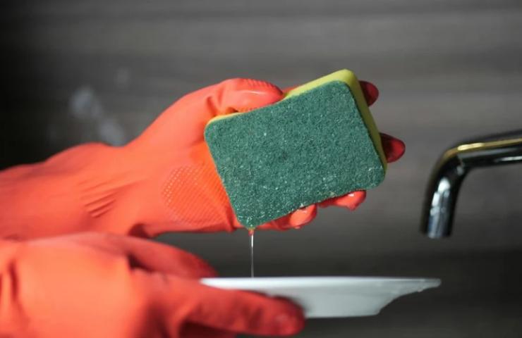 Persona lava i piatti con una spugnetta