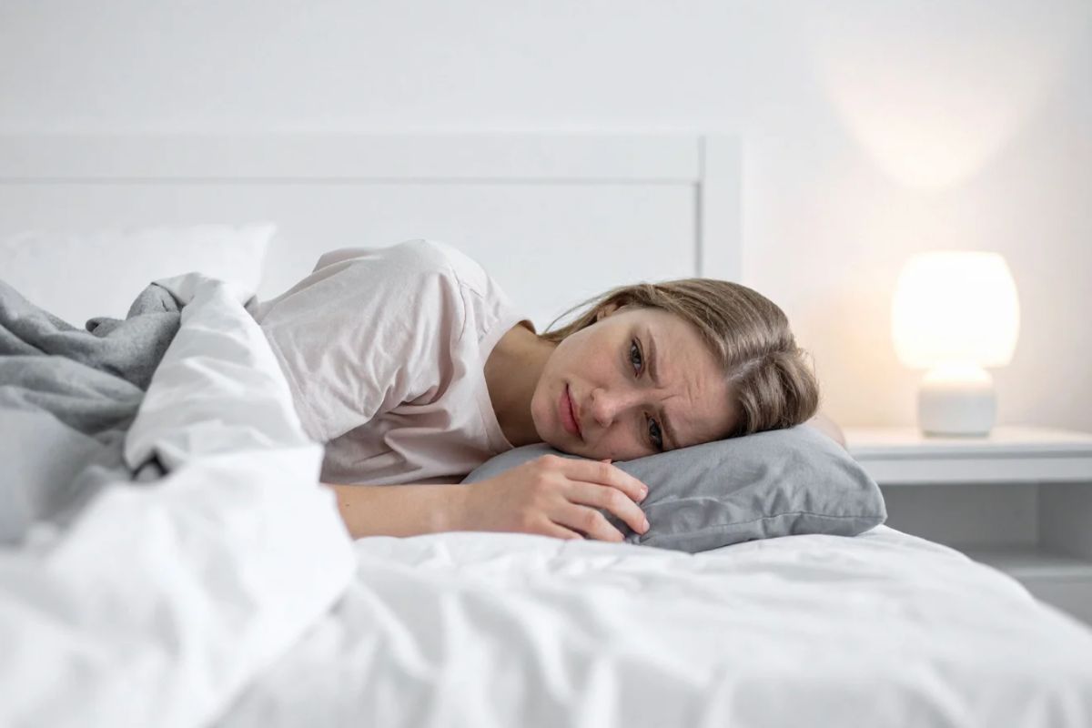 Donna sdraiata nel letto con espressione affranta