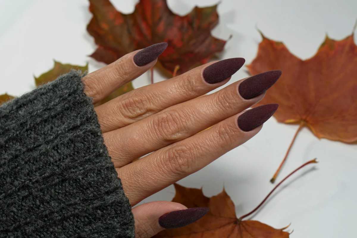 Unghie marrone scuro con foglie marroni sullo sfondo